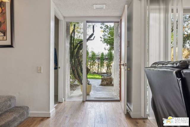 entryway featuring floor to ceiling windows, a textured ceiling, and light hardwood / wood-style floors