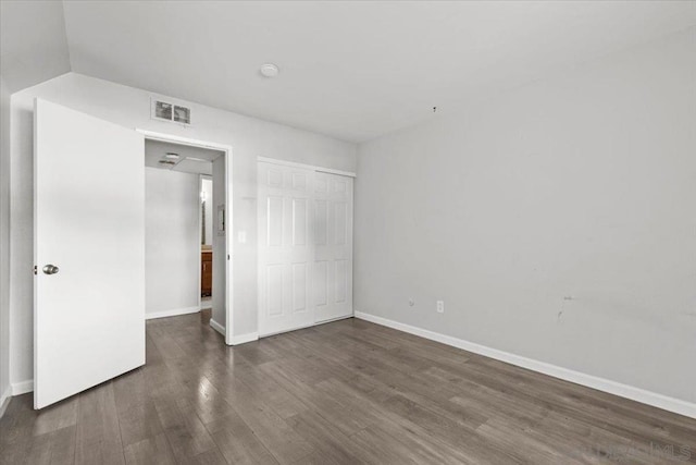 unfurnished bedroom featuring a closet and dark hardwood / wood-style floors