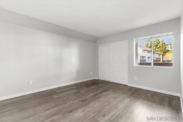 unfurnished bedroom with dark hardwood / wood-style flooring and a closet