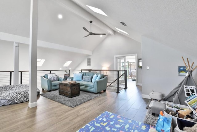 living room featuring beam ceiling, a skylight, high vaulted ceiling, and light hardwood / wood-style flooring