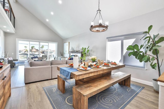 dining space featuring high vaulted ceiling, light hardwood / wood-style flooring, and a notable chandelier