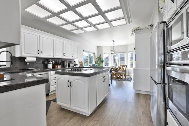 kitchen featuring sink, tasteful backsplash, decorative light fixtures, appliances with stainless steel finishes, and white cabinets