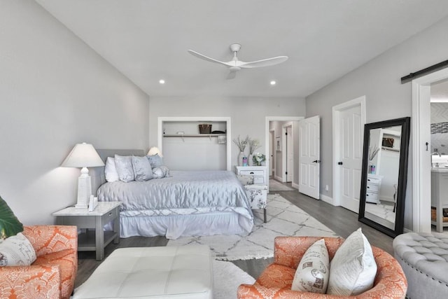 bedroom with hardwood / wood-style flooring, a barn door, and ceiling fan