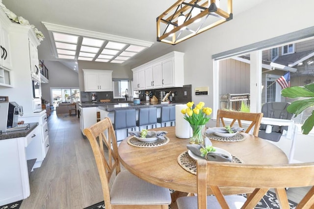 dining area with wood-type flooring, vaulted ceiling, and sink