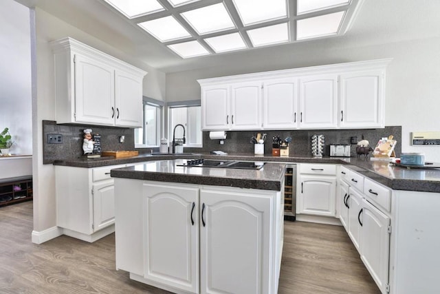 kitchen with sink, light hardwood / wood-style flooring, white cabinetry, a center island, and black electric stovetop