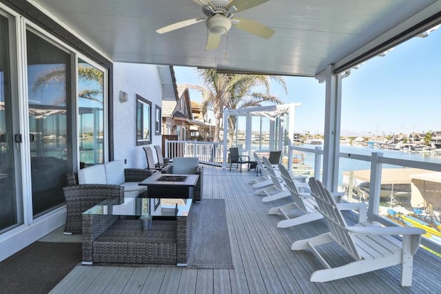 wooden terrace featuring a water view, an outdoor living space with a fire pit, and ceiling fan