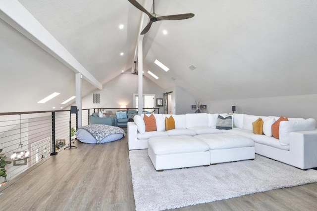 living room featuring lofted ceiling with skylight, ceiling fan, and light wood-type flooring