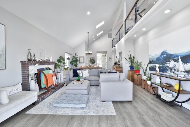 living room featuring a chandelier, high vaulted ceiling, and light wood-type flooring