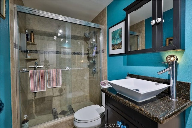 bathroom featuring an enclosed shower, vanity, and toilet