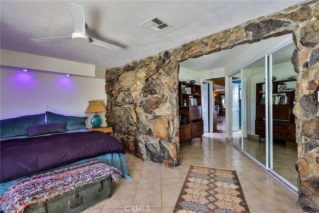 bedroom featuring light tile patterned floors, ceiling fan, and a closet