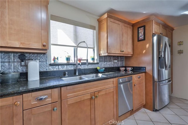 kitchen featuring sink, tasteful backsplash, light tile patterned floors, dark stone countertops, and stainless steel fridge