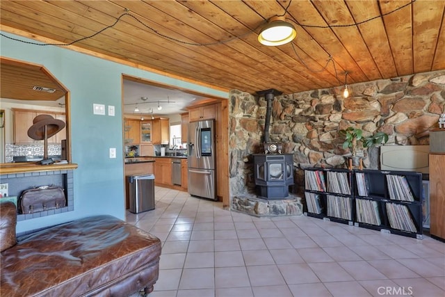 interior space featuring a wood stove, wooden ceiling, and light tile patterned flooring