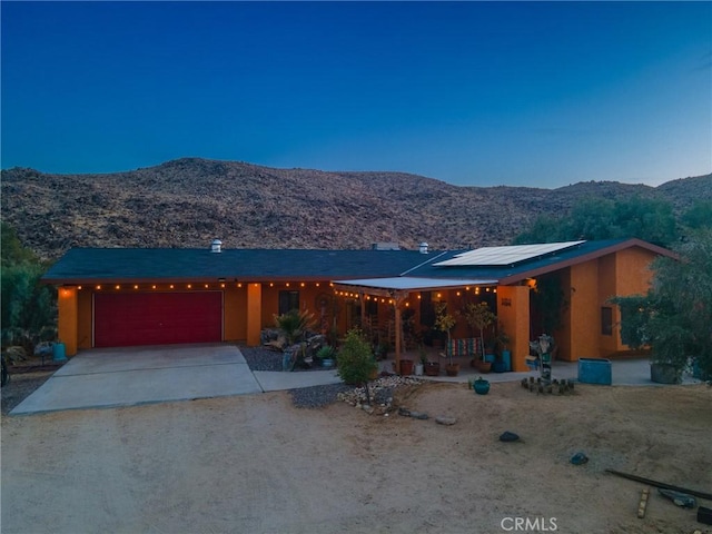 view of front of property with a mountain view, a garage, and solar panels