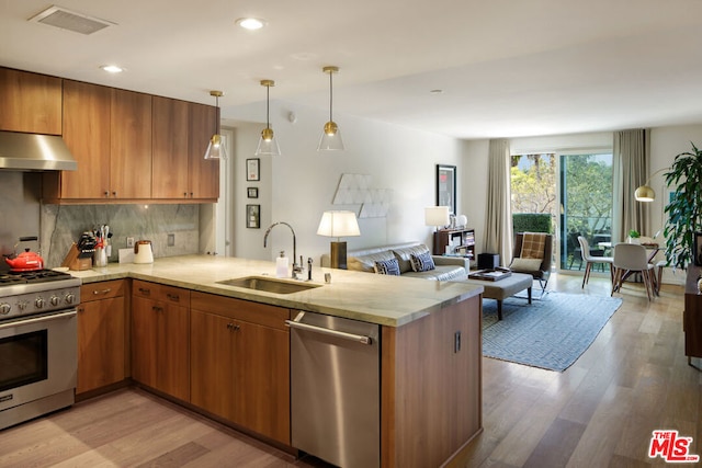 kitchen featuring stainless steel appliances, kitchen peninsula, sink, and light hardwood / wood-style flooring