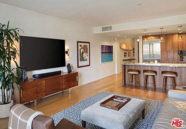 living room featuring sink and light hardwood / wood-style flooring