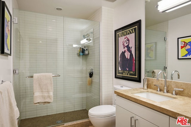 bathroom featuring vanity, toilet, and a shower with shower door