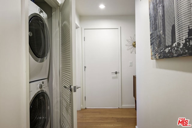 washroom with wood-type flooring and stacked washer / drying machine