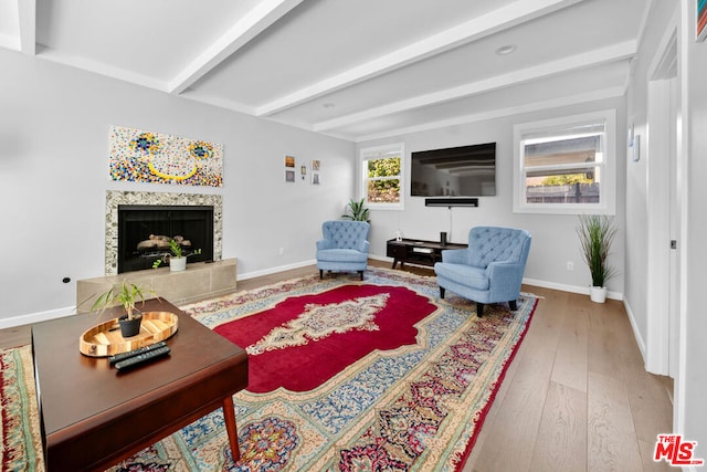 living room featuring beamed ceiling, wood-type flooring, and a fireplace