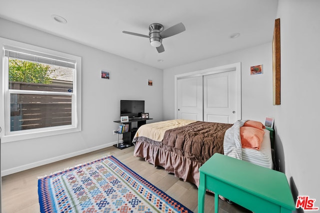 bedroom with light hardwood / wood-style flooring, ceiling fan, and a closet