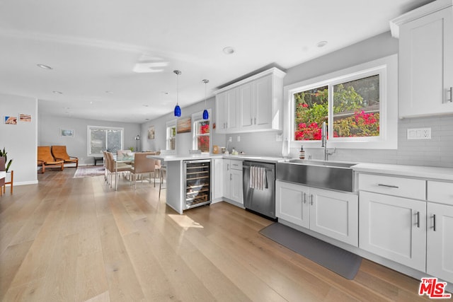 kitchen featuring decorative light fixtures, sink, beverage cooler, stainless steel dishwasher, and kitchen peninsula