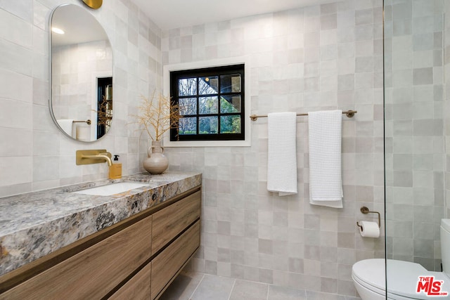 bathroom featuring tile walls, vanity, tile patterned floors, and toilet