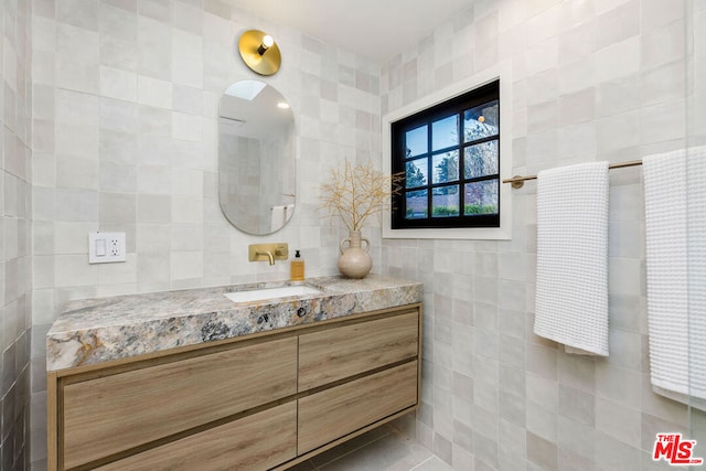 bathroom with tile patterned floors, vanity, and tile walls