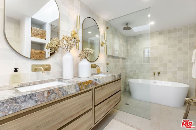 bathroom featuring a tub to relax in, tile patterned flooring, tile walls, and vanity