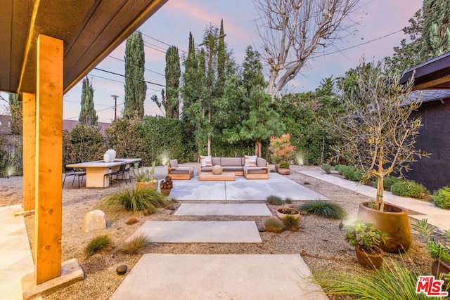 yard at dusk featuring an outdoor living space and a patio area