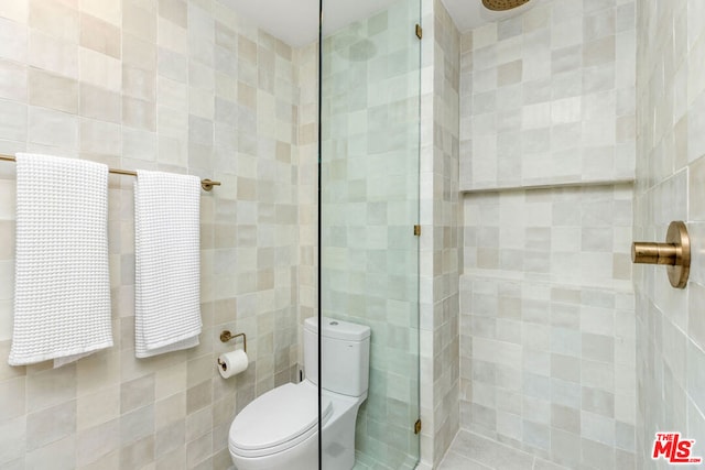 bathroom with a tile shower, tile walls, and toilet