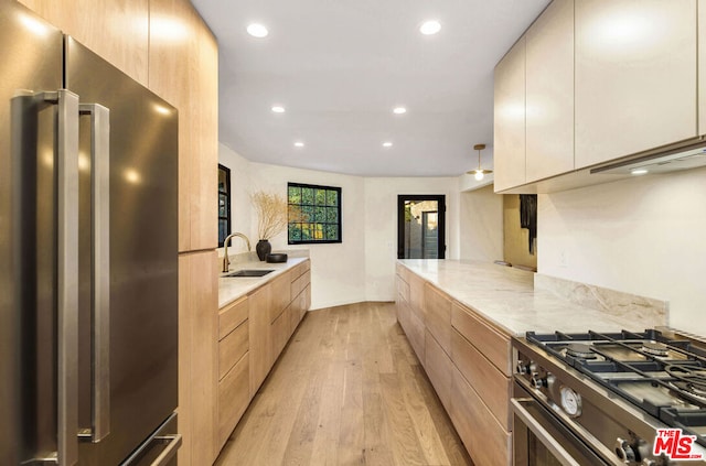 kitchen featuring sink, light stone counters, stainless steel appliances, light hardwood / wood-style floors, and white cabinets