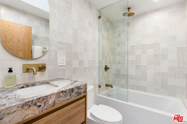 full bathroom with tiled shower / bath, tile walls, backsplash, vanity, and toilet