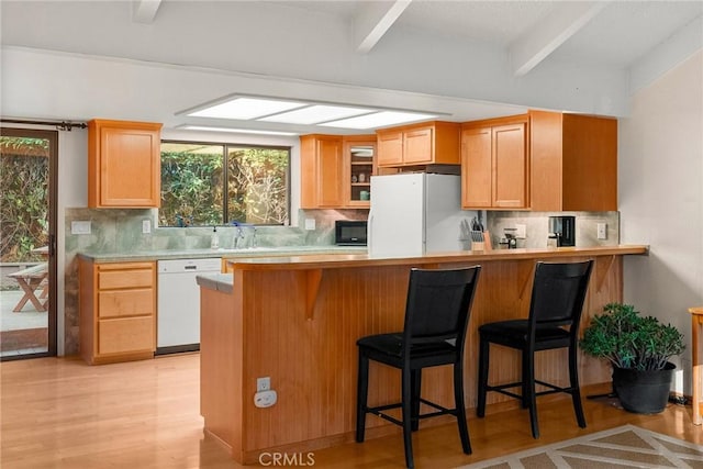 kitchen featuring beamed ceiling, a breakfast bar area, backsplash, and white appliances