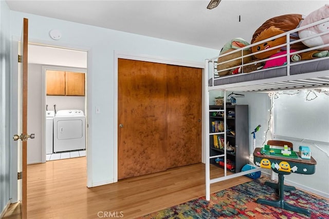 bedroom with a closet, washer and dryer, and light wood-type flooring