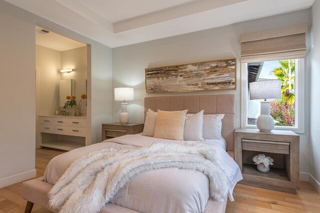 bedroom featuring ensuite bath and light wood-type flooring