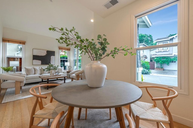 dining area with wood-type flooring and vaulted ceiling