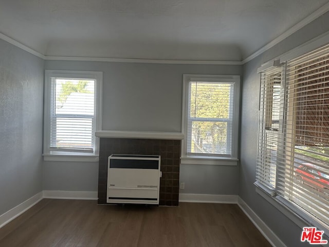 unfurnished living room with ornamental molding, dark wood-type flooring, heating unit, and a fireplace