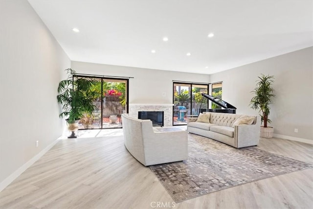 living room with a high end fireplace and light hardwood / wood-style flooring