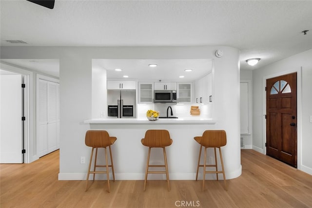 kitchen featuring sink, white cabinets, a kitchen breakfast bar, kitchen peninsula, and stainless steel appliances