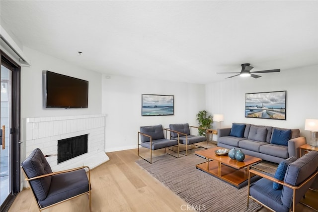 living room featuring ceiling fan, a fireplace, and light hardwood / wood-style floors