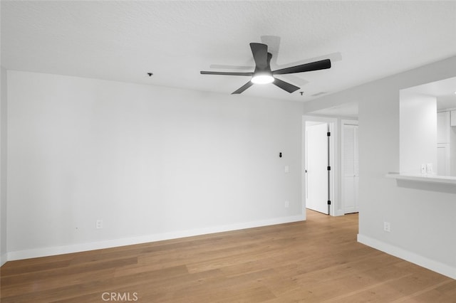 empty room featuring ceiling fan, light hardwood / wood-style floors, and a textured ceiling