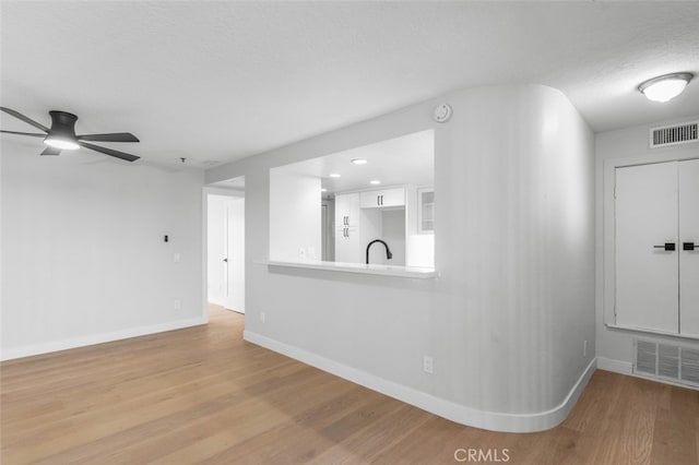 empty room with ceiling fan, sink, a textured ceiling, and light wood-type flooring