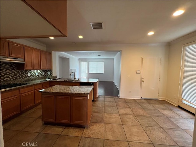 kitchen with sink, dark stone countertops, backsplash, a center island, and kitchen peninsula