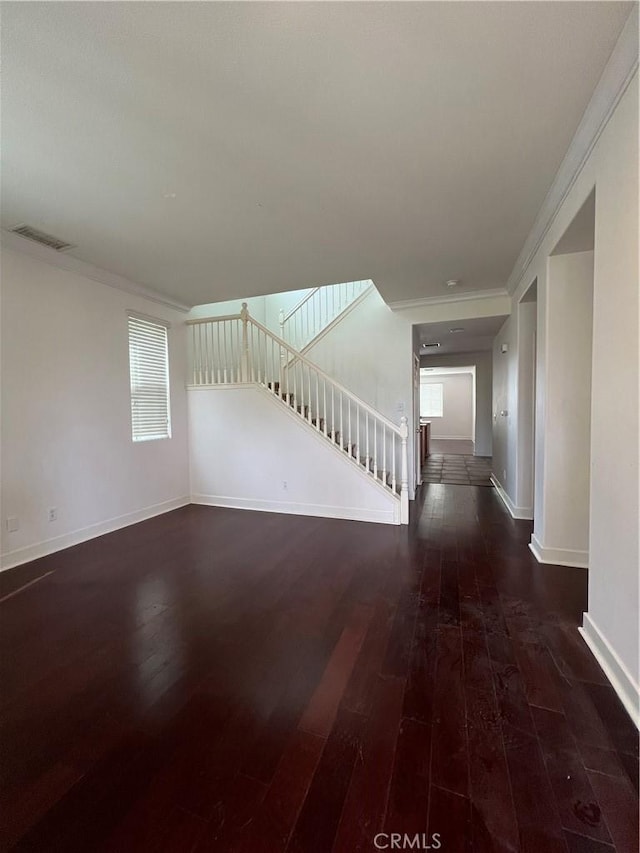 unfurnished living room with ornamental molding and dark wood-type flooring