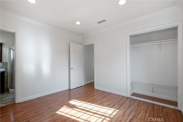 unfurnished bedroom with hardwood / wood-style flooring, ornamental molding, and a closet