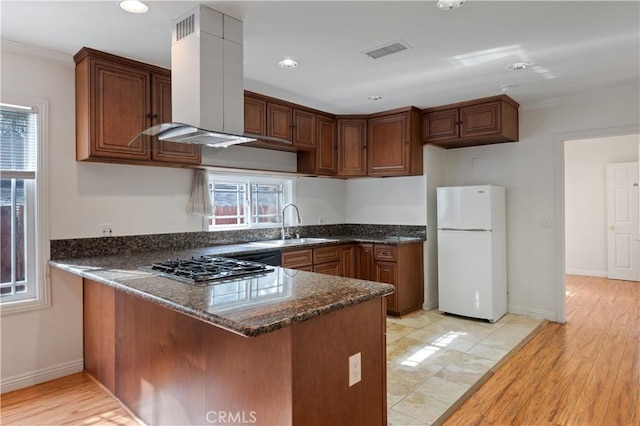 kitchen featuring sink, stainless steel gas cooktop, island exhaust hood, kitchen peninsula, and white fridge