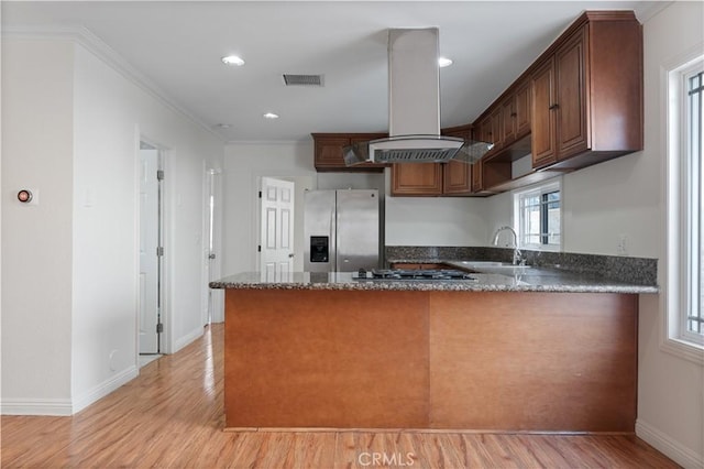 kitchen with island exhaust hood, kitchen peninsula, dark stone counters, and appliances with stainless steel finishes