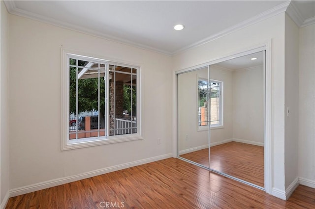 unfurnished bedroom featuring ornamental molding, hardwood / wood-style floors, and a closet