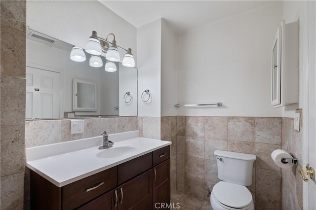 bathroom with vanity, toilet, and tile walls