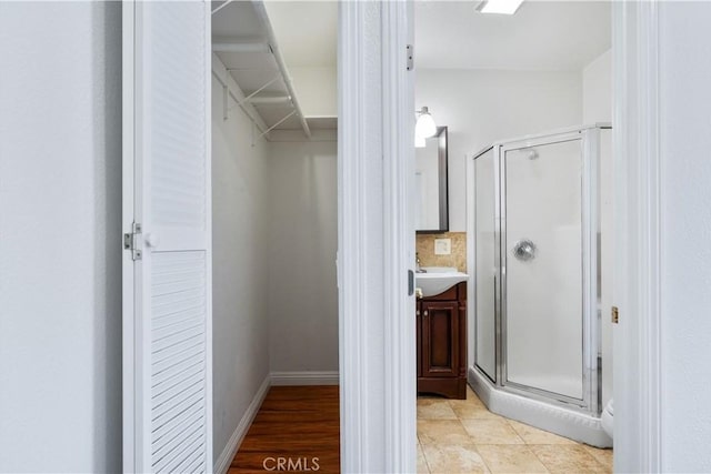 bathroom featuring vanity, a shower with shower door, and backsplash