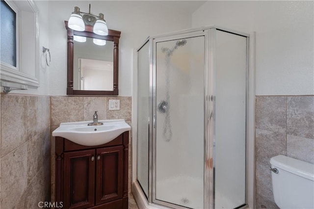 bathroom with tile walls, vanity, toilet, and walk in shower